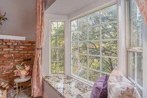A room with a large window, a brick wall, a small round table with a vase, and a sofa. - The Best Lake View!! (Crestline)