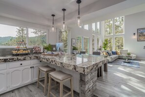A modern kitchen with a large island, bar stools, and a view of the outdoors. - The Best Lake View!! (Crestline)