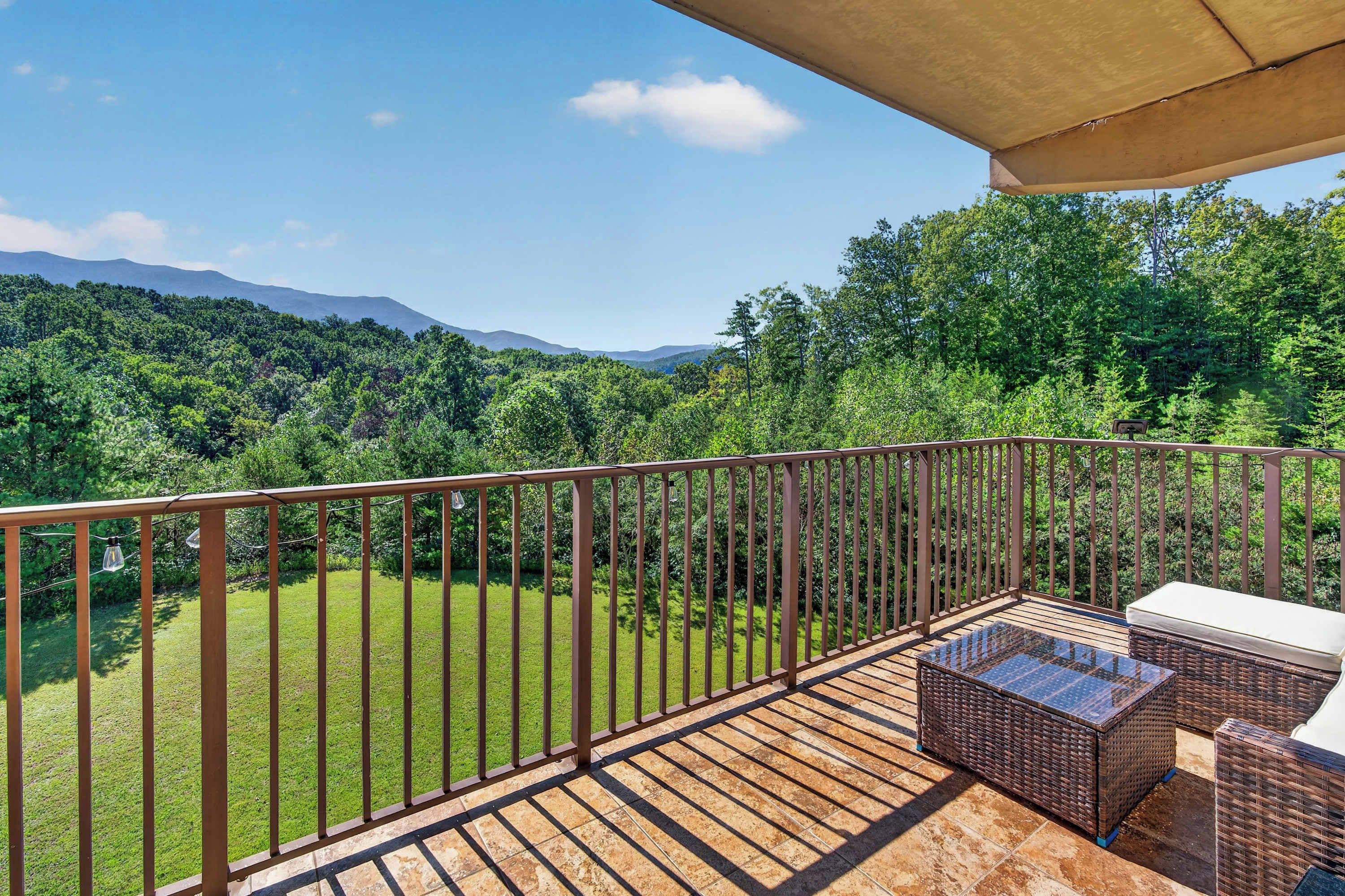 A balcony with a view of a green landscape and mountains.
