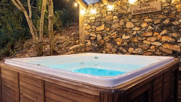 Un jacuzzi en una cabaña de madera con un muro de piedra y un letrero que dice 'ZONA COMPARTIDA'.
