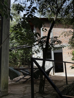 Un patio con un edificio de ladrillo, una hamaca y una cerca de metal.