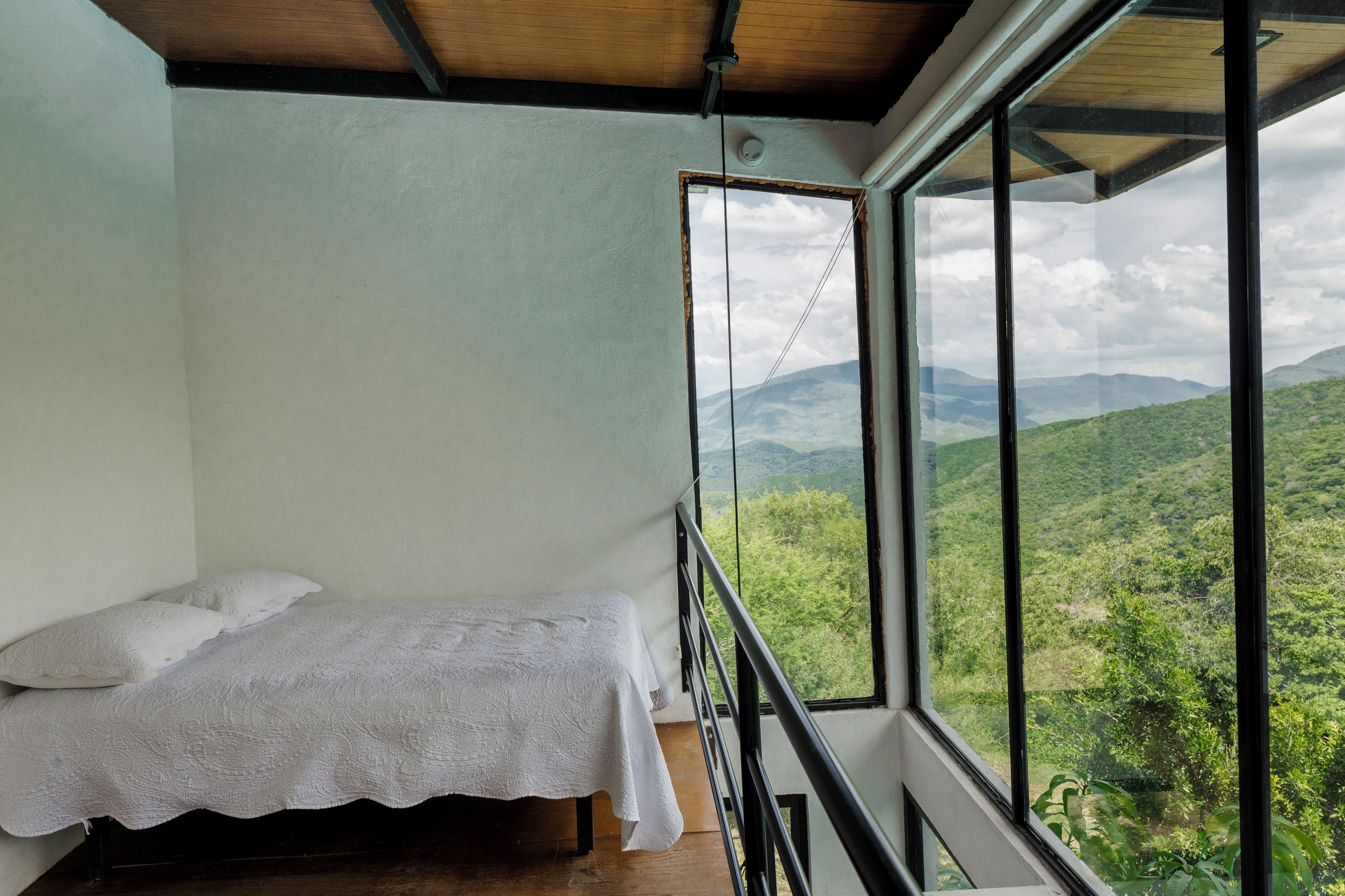Une chambre avec un lit, une fenêtre donnant sur les montagnes et un plafond avec des poutres en bois.