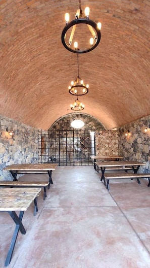 An interior with arched ceilings, stone walls, and multiple tables with benches.