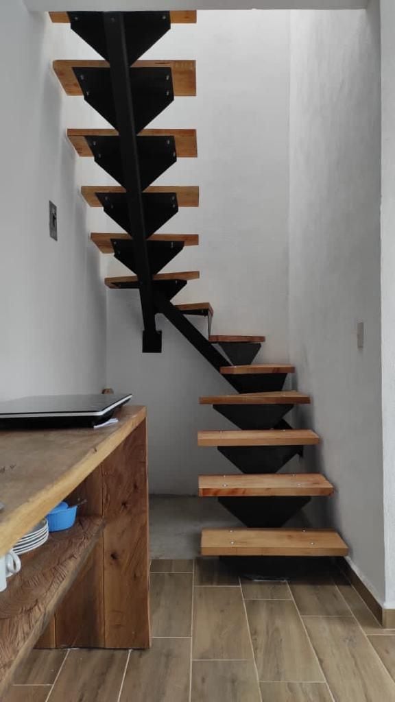 Un escalier avec des marches en bois et une rampe en métal noir.