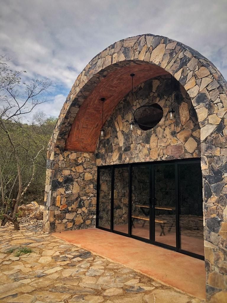 A stone building with an arched entrance and a glass door.