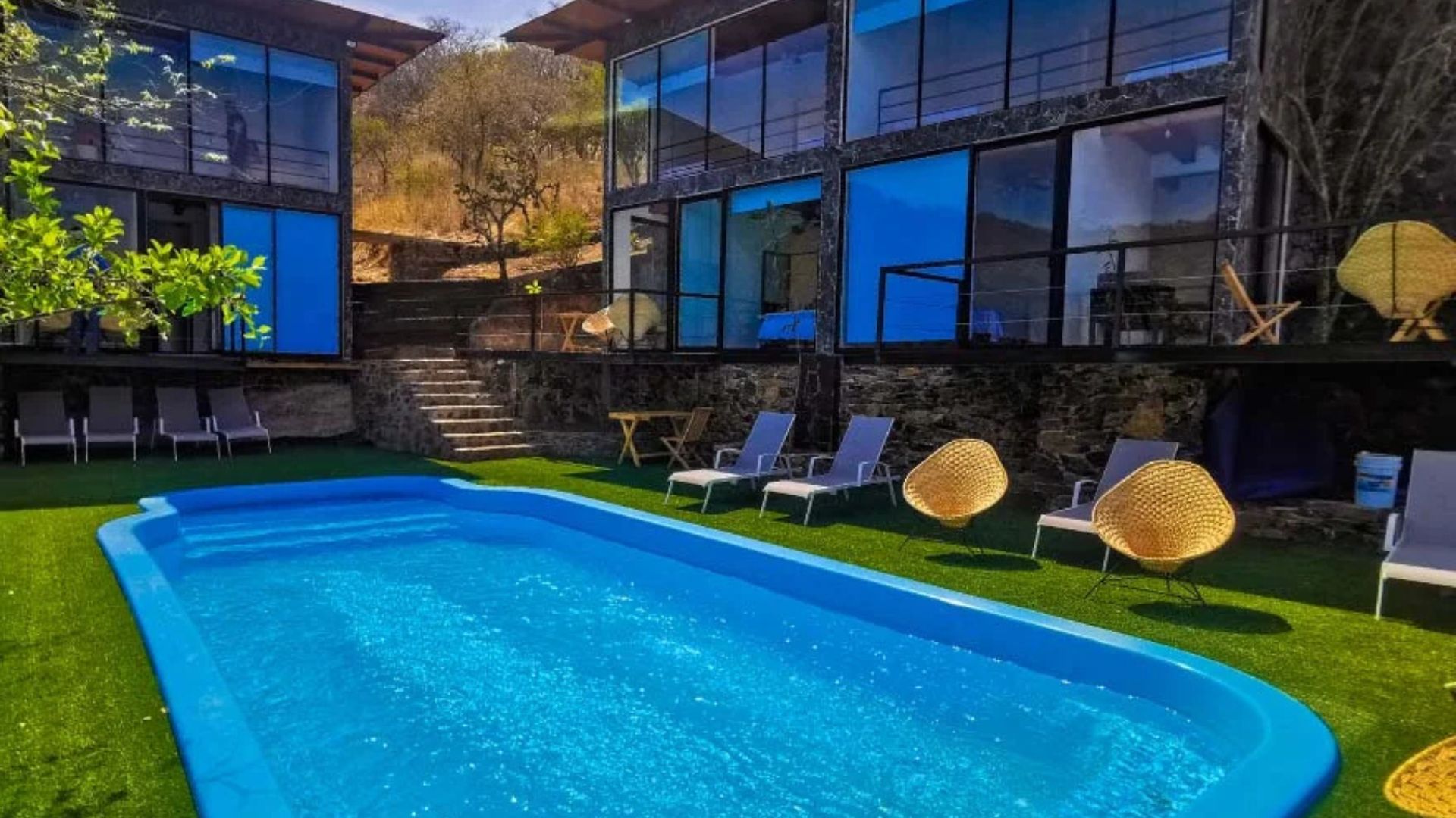 A swimming pool with lounge chairs and a stone wall.