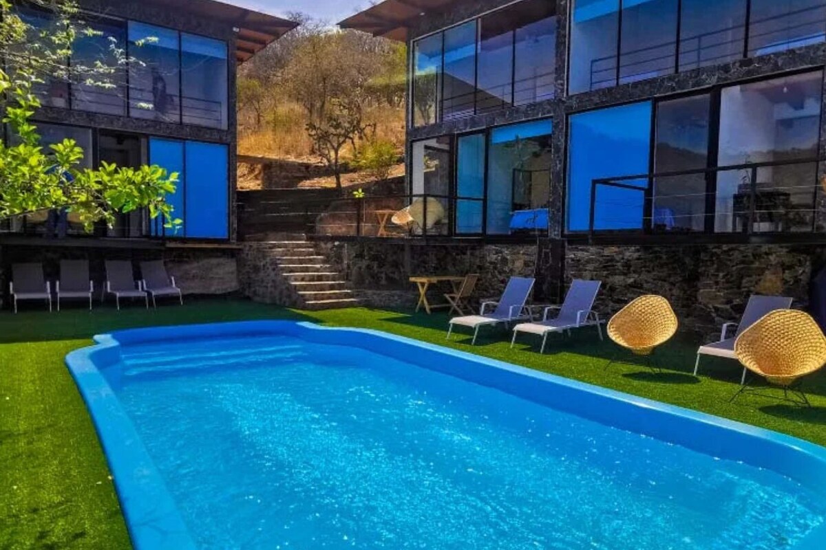 A swimming pool with lounge chairs and a stone wall.