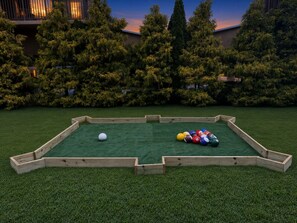 A pool table with a wooden frame and a green felt surface, surrounded by a grassy area with trees in the background. - View, Sauna, Free Spa, Dolly, and Anakeesta 155, (Gatlinburg)