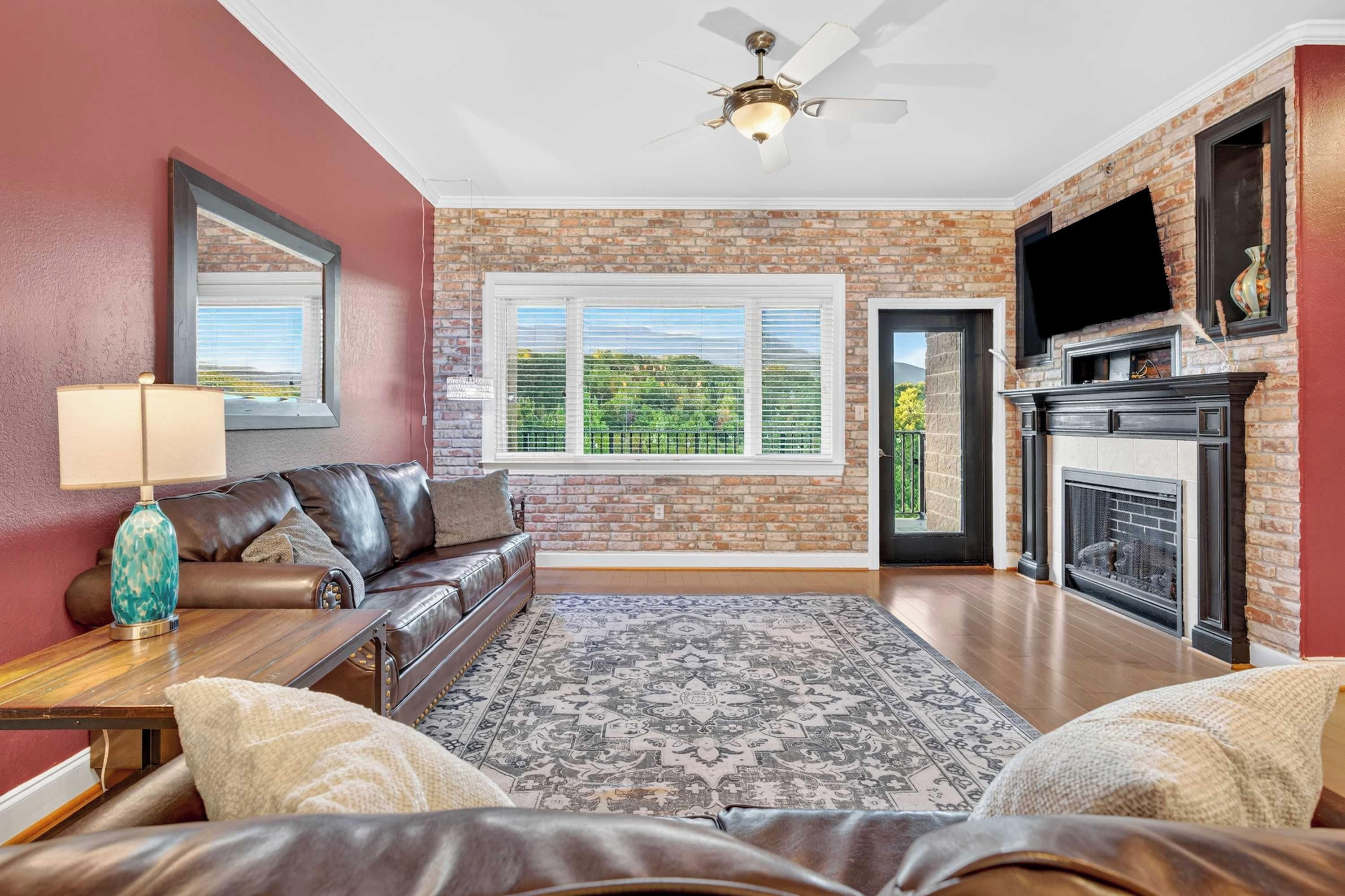 A living room with a leather sofa, a patterned rug, a fireplace, and a television mounted on the wall.