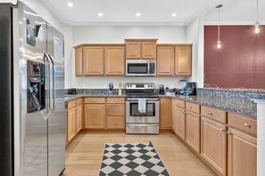 A kitchen with wooden cabinets, stainless steel appliances, granite countertops, and a checkered rug. - View, Sauna, Free Spa, Dolly, and Anakeesta 155, (Gatlinburg)