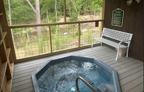 A hot tub with a wooden deck and a white bench, surrounded by a fenced area with trees. - Hot Tub, Free Dollywood, Anakes, Sauna, Hot Spring (Gatlinburg)