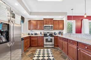 A kitchen with wooden cabinets, stainless steel appliances, a checkered floor, and a red accent wall. - Luxury Gatlinburg Condo Free Dollywood w/ Sauna (Gatlinburg)