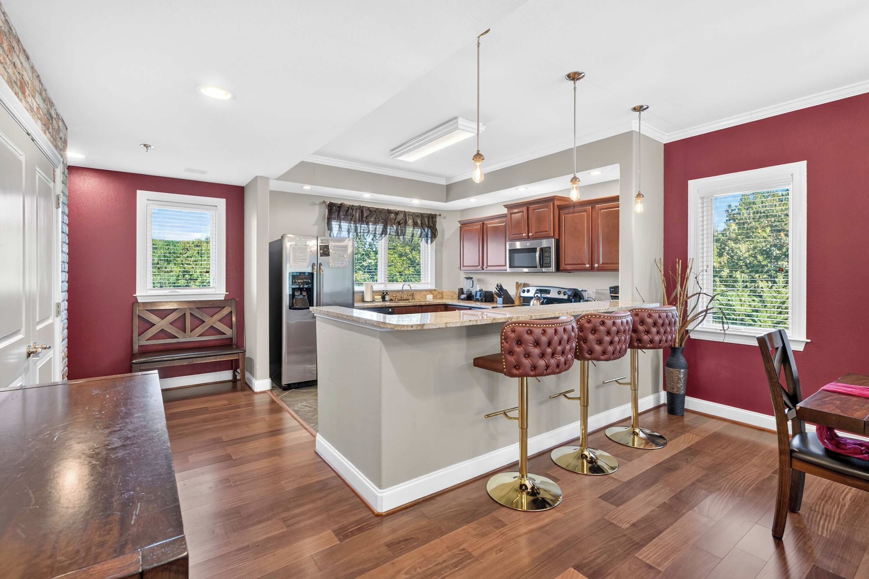 A modern kitchen with a central island, bar stools, and pendant lighting.
