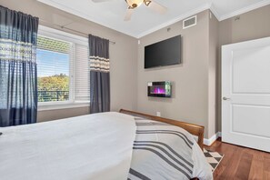 Ein Schlafzimmer mit einem Bett, einem flachbildfernseher an der Wand und einer Tür.