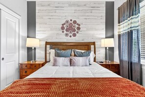 A hotel room with a wooden headboard, a patterned wall, two bedside tables with lamps, and a window with curtains. - Penthouse w/ Sauna, Arcade, Free Dollywood Tickets (Gatlinburg)