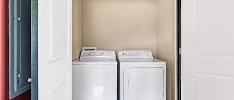A laundry room with two white washing machines and a dryer.