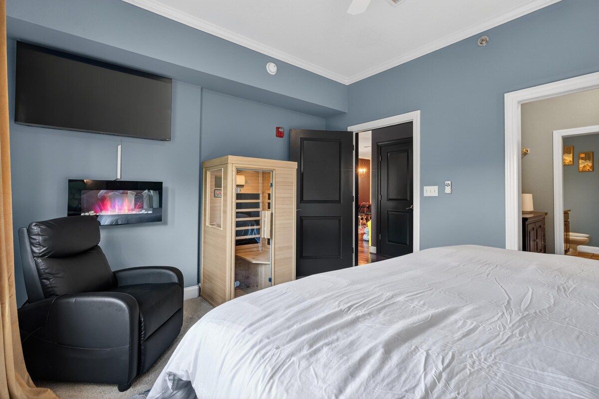 A bedroom with a bed, a TV, a wardrobe, and a door leading to another room.