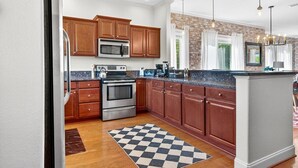 A kitchen with wooden cabinets, stainless steel appliances, and a checkered floor mat. - Gatlinburg Condo: Sauna, Arcade, Spa, Incredible (Gatlinburg)