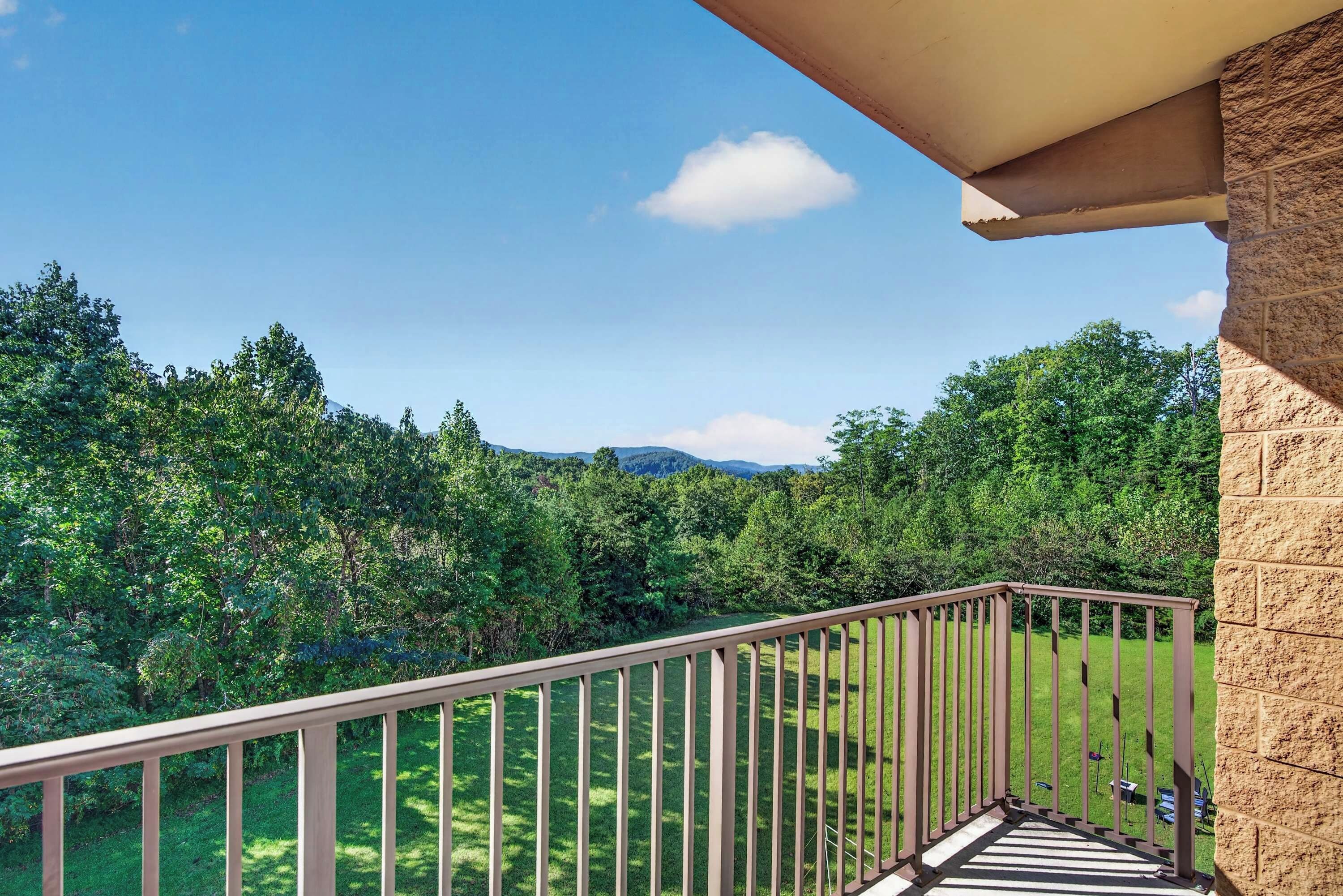 Un balcone con vista su un paesaggio verde e montagne sullo sfondo.