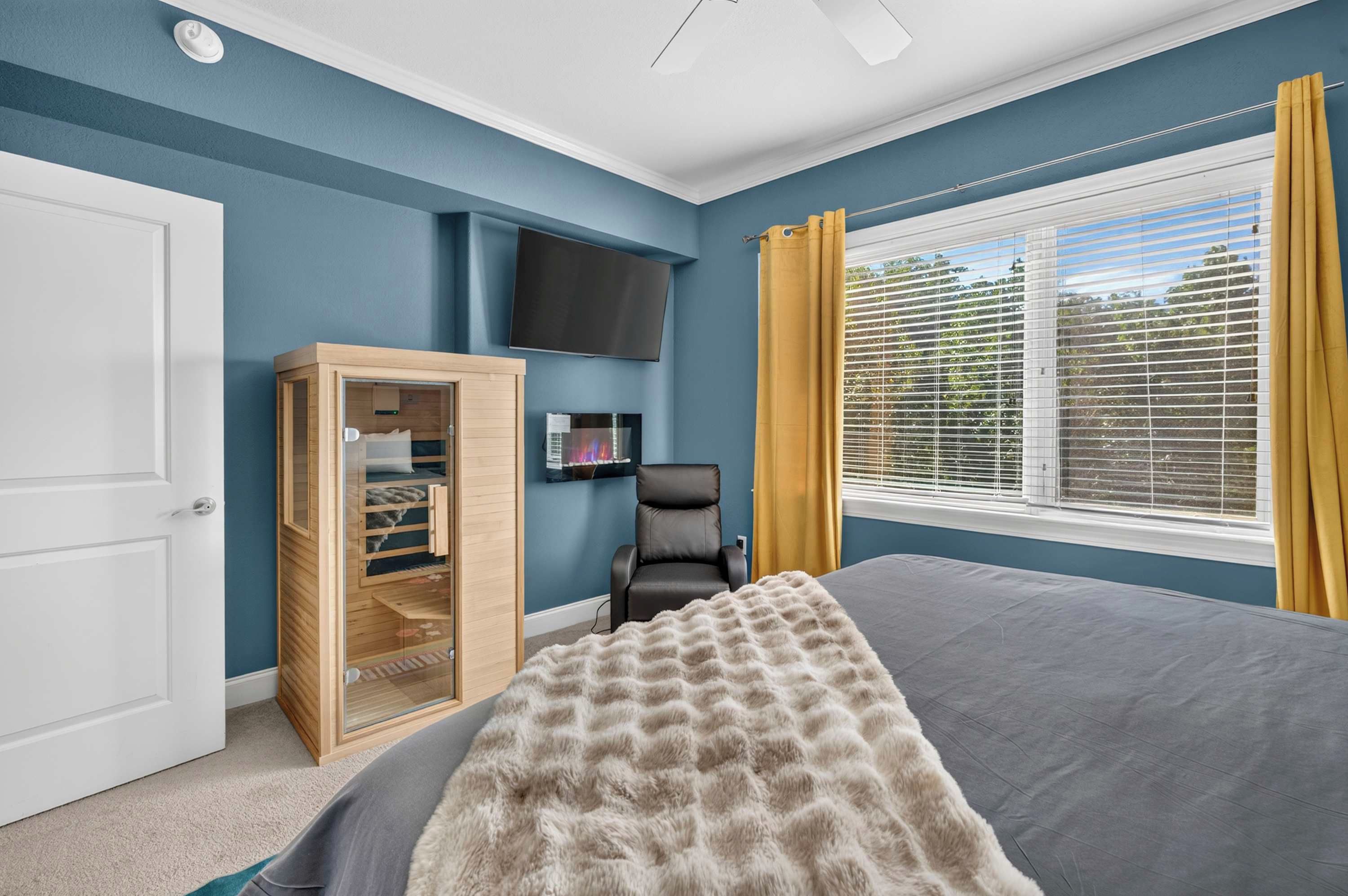 A bedroom with a bed, a wardrobe, a television, and a window with curtains.
