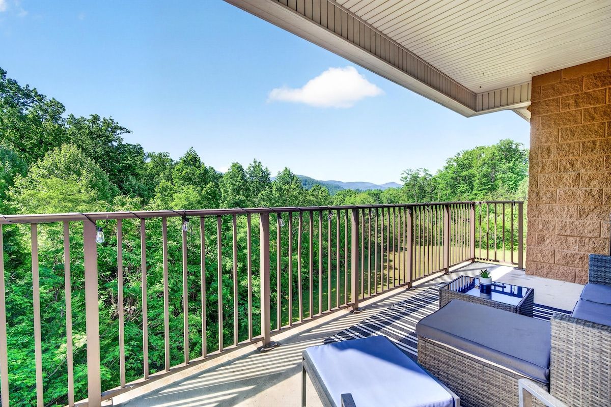 Ein Balkon mit Gartenmöbeln, einer Steinmauer und Blick auf einen bewaldeten Bereich.