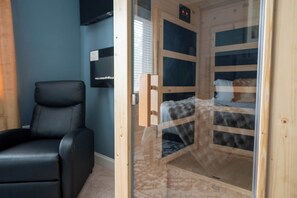 A room with a sauna, a black leather chair, and a bed with a patterned cover. - Sauna & Spa Paradise 1 Mi from Downtown Gatlinburg (Gatlinburg)