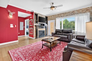 A living room with a fireplace, a leather sofa, a coffee table, and a red patterned rug. - Sauna & Spa Paradise 1 Mi from Downtown Gatlinburg (Gatlinburg)