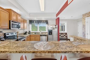 A kitchen with granite countertops, wooden cabinets, a stainless steel refrigerator, and a microwave. - Sauna & Spa Paradise 1 Mi from Downtown Gatlinburg (Gatlinburg)