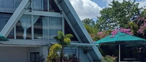 Un edificio moderno con piscina, rodeado de vegetación y un cielo despejado.