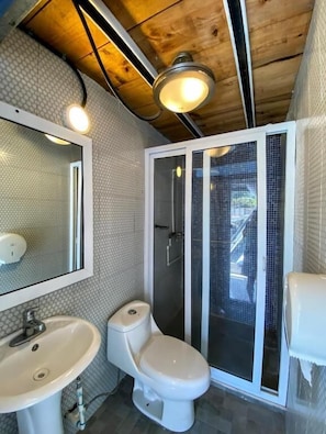 Un bagno con lavandino, WC e box doccia, tutto in bianco.