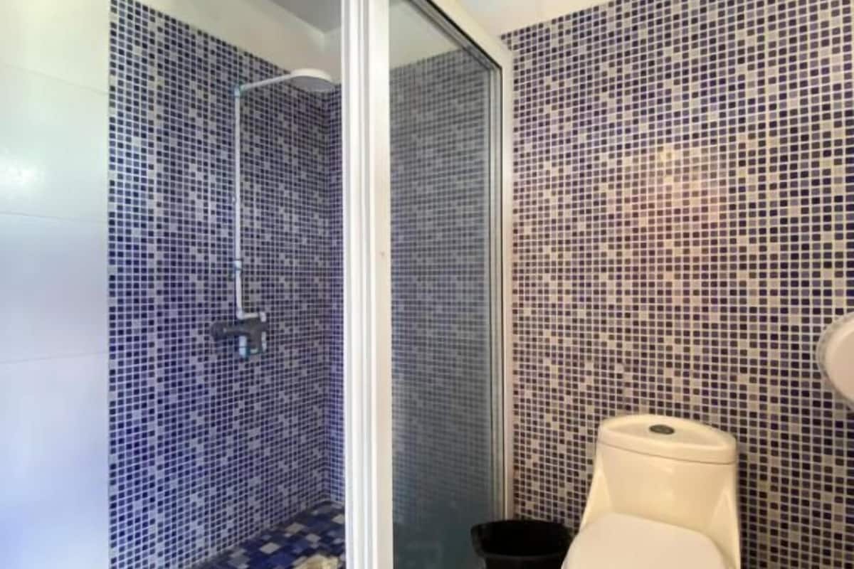 A bathroom with a shower, toilet, and tiled floor.