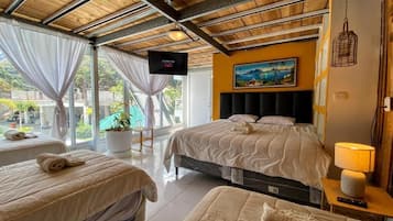 Una habitación de hotel con cama, sofá, televisor y un cuadro en la pared.