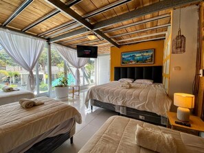 Una camera d'albergo con un letto, un divano, una TV e un quadro appeso al muro.