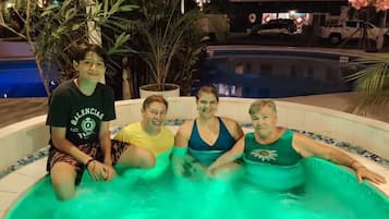Un grupo de personas sentadas en un jacuzzi con una piscina al fondo.