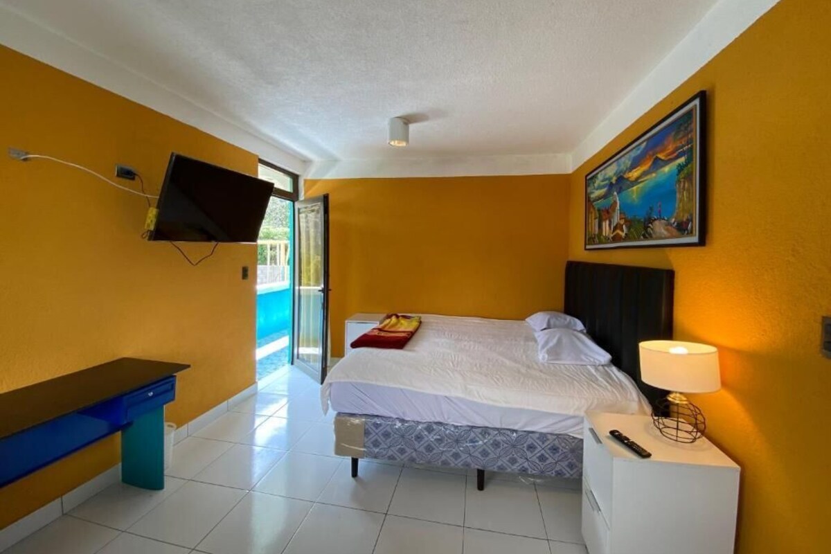 Una camera d'albergo con un letto, un comodino, una lampada e un quadro appeso al muro.