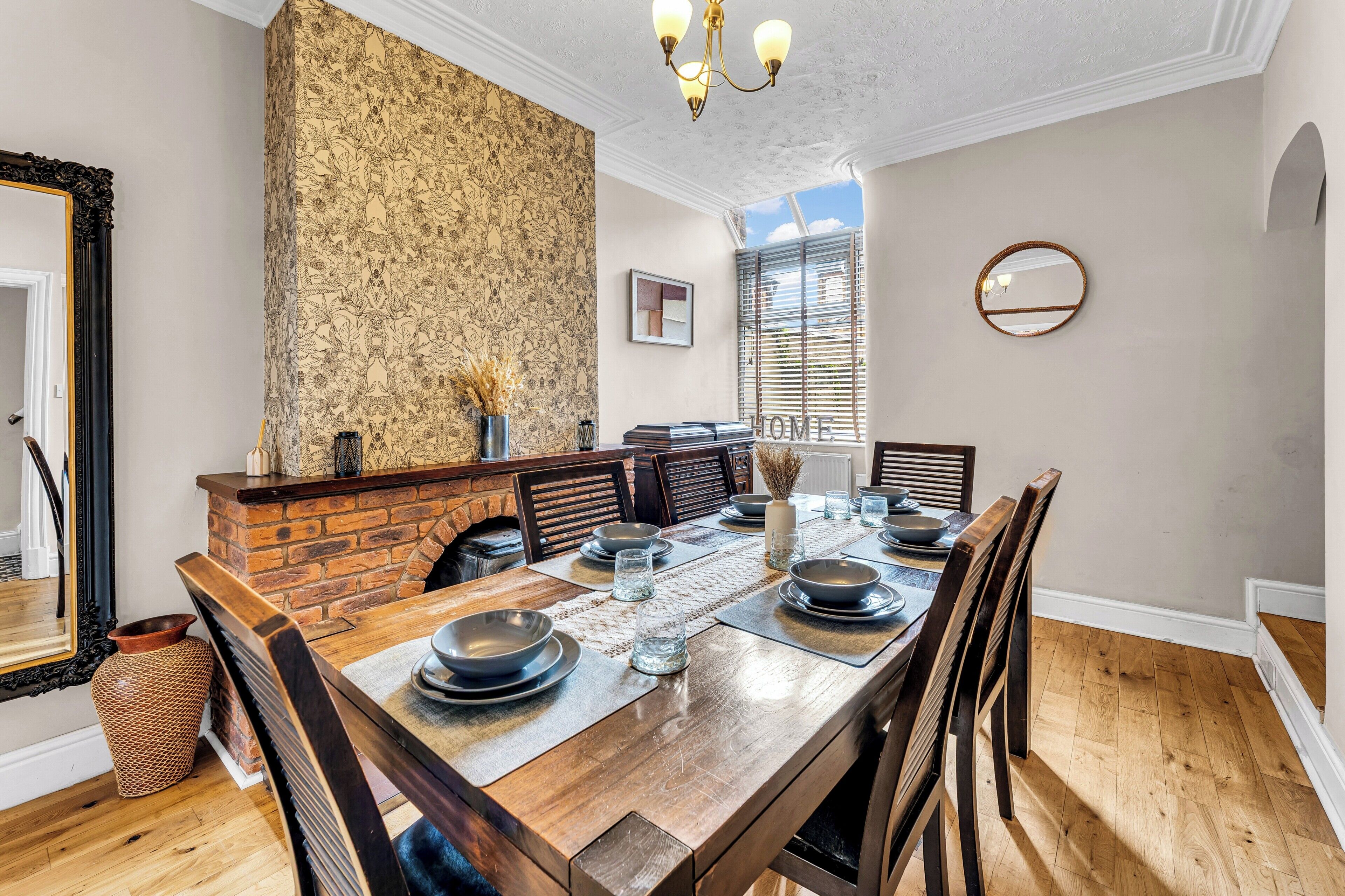 A dining room with a brick fireplace, wooden table, and chairs.