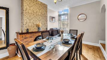 A dining room with a brick fireplace, wooden table, and chairs.