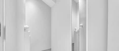 A white bathroom with a large mirror, a shower area, and a door with a handle.