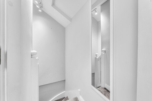 A white bathroom with a large mirror, a shower area, and a door with a handle.