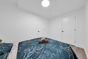 Een slaapkamer met een bed, nachtkastje en een wandplank.