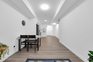 Un intérieur moderne comprenant un coin repas, une cuisine et un couloir menant à une porte.