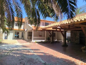 A courtyard with a tiled floor, a covered seating area, and a building with a tiled roof. - Beachfront House (Magdalena)