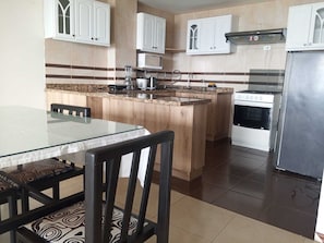 A kitchen with a central island, white cabinets, a stainless steel refrigerator, and a microwave. - American Embassy area, family-friendly, excellent view of the northern part of the city (Quito)