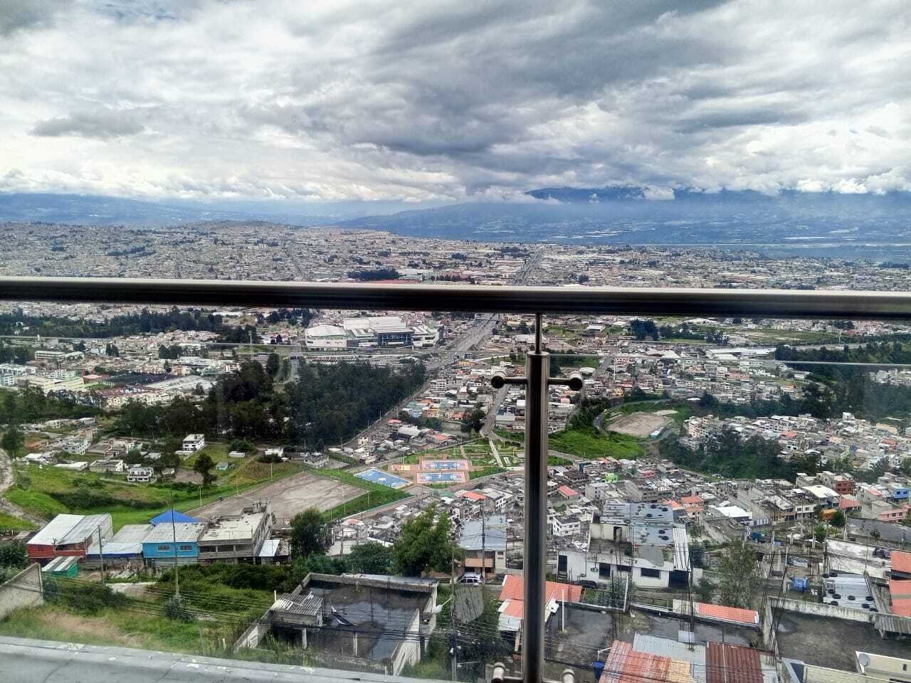 Un paisaje urbano con edificios, carreteras y una cadena montañosa distante.