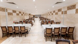 Un salón de conferencias con varias mesas y sillas dispuestas en filas.