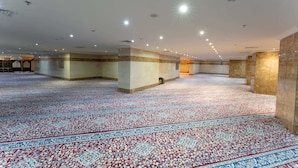 Un amplio salón con alfombra estampada, múltiples columnas e iluminación empotrada.