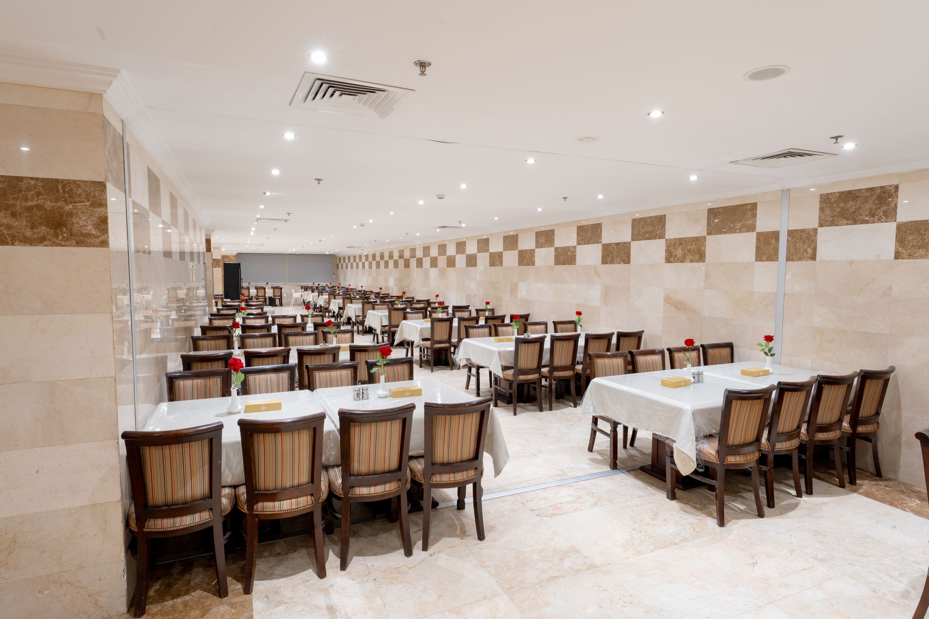 A spacious dining area with multiple tables and chairs, arranged in rows.
