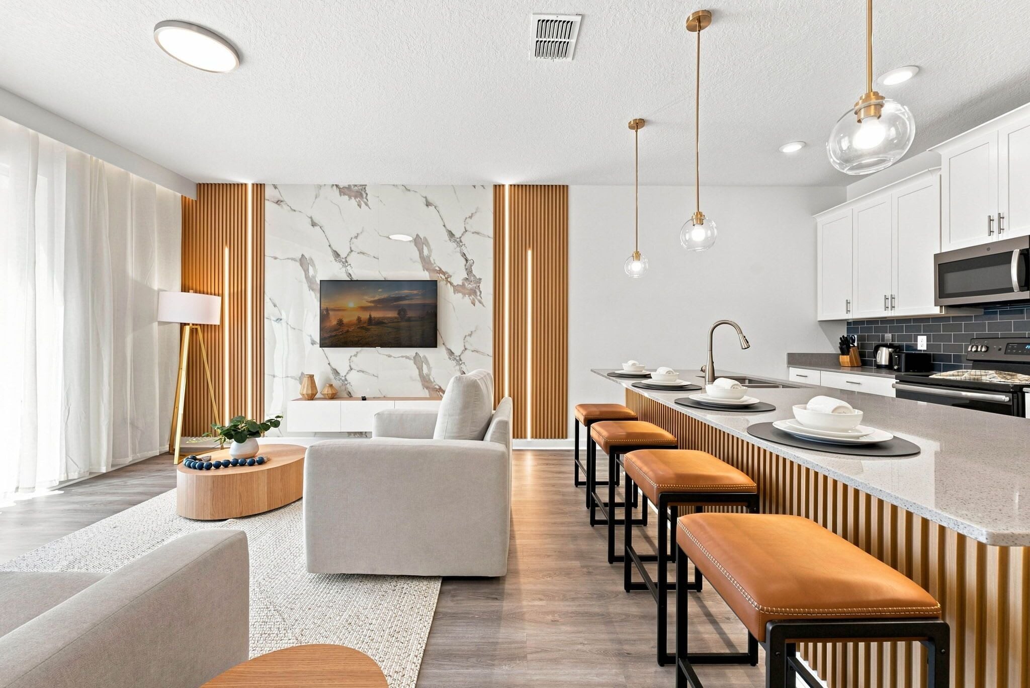 Eine moderne Küche mit Kochinsel, Barhocker und Essbereich mit einer Couch.