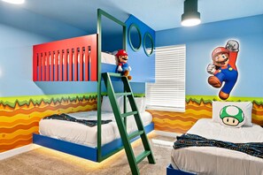 Ein Schlafzimmer mit einem Etagenbett, einer Leiter, einem Fenster mit Jalousien und einer Wand mit einem Mario-Charakter.
