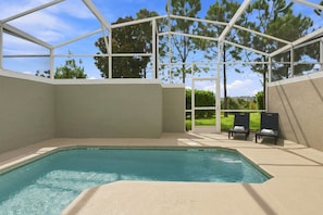 Ein überdachter Pool mit freiem Blick auf die umliegenden Bäume und eine Terrasse mit Liegestühlen.